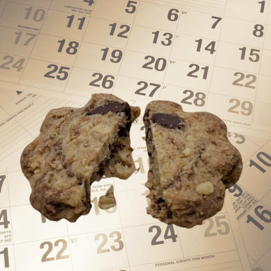 Un cookie artisanal aux pépites de chocolat posé sur un calendrier pour illustrer la durée de conservation des biscuits sans conservateurs.